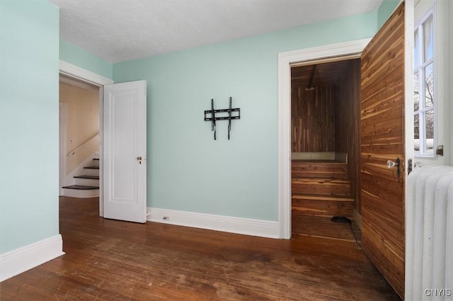 empty room featuring dark hardwood / wood-style flooring and radiator heating unit