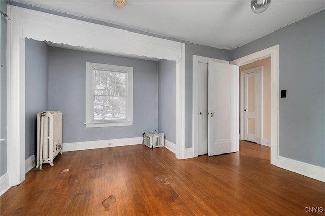 unfurnished bedroom with wood-type flooring and radiator heating unit