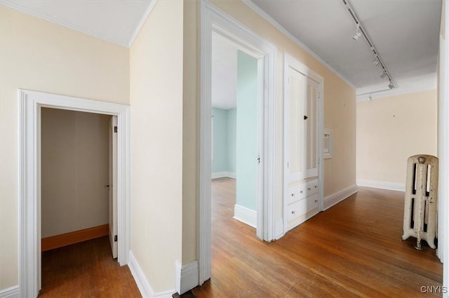 hallway with radiator, hardwood / wood-style floors, crown molding, and rail lighting