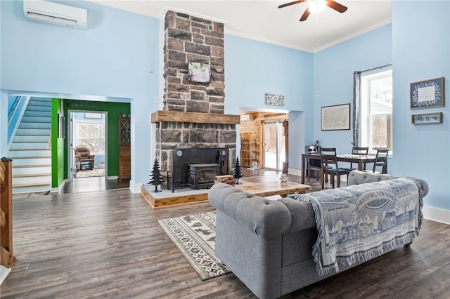 living room featuring an AC wall unit, ornamental molding, a wealth of natural light, and a wood stove