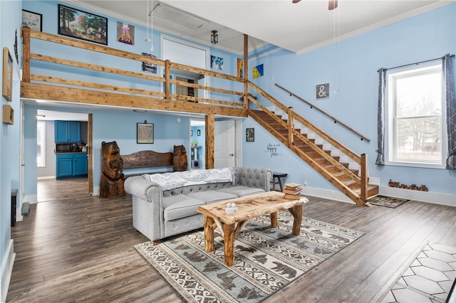 living room featuring ceiling fan, ornamental molding, wood-type flooring, and a high ceiling