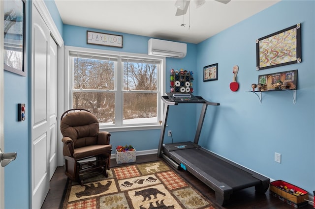 exercise room with hardwood / wood-style flooring, an AC wall unit, and ceiling fan