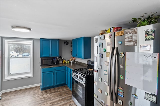 kitchen with blue cabinetry, appliances with stainless steel finishes, and dark hardwood / wood-style flooring