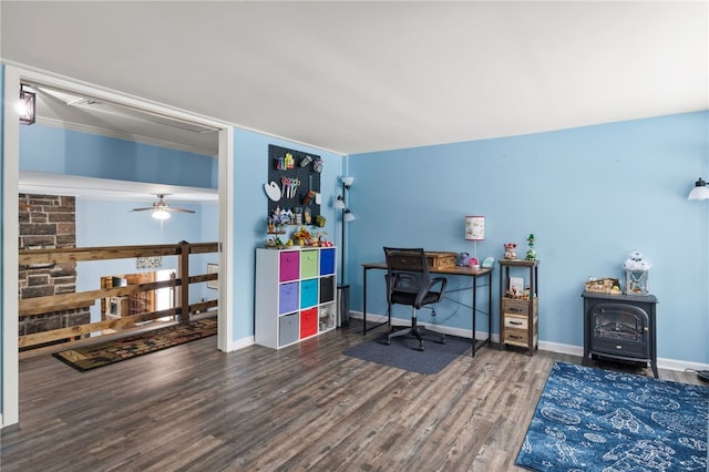 office space featuring dark wood-type flooring, ceiling fan, and a wood stove