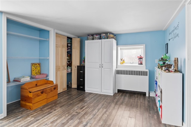 bedroom featuring radiator heating unit and dark hardwood / wood-style flooring