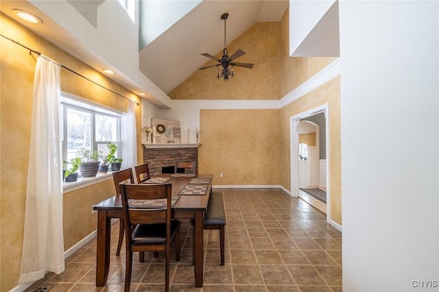 tiled dining space with ceiling fan and a towering ceiling