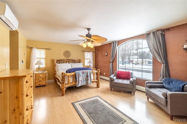 bedroom featuring a wall unit AC, ceiling fan, light wood-type flooring, and multiple windows