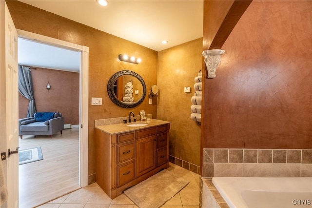 bathroom with tile patterned flooring, a relaxing tiled tub, and vanity