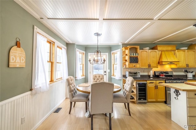 dining space featuring beverage cooler, a notable chandelier, and light wood-type flooring