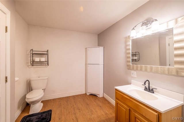 bathroom with toilet, vanity, and hardwood / wood-style flooring