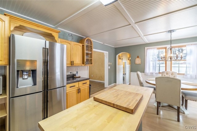 kitchen featuring decorative light fixtures, a notable chandelier, stainless steel refrigerator with ice dispenser, decorative backsplash, and light hardwood / wood-style flooring