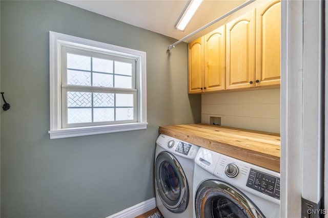 clothes washing area featuring cabinets and washer and clothes dryer