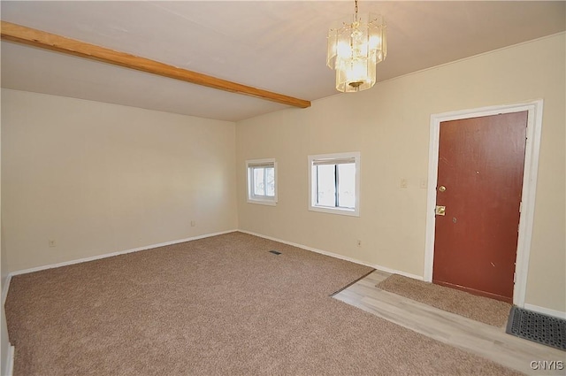 empty room with carpet flooring, beam ceiling, and a chandelier