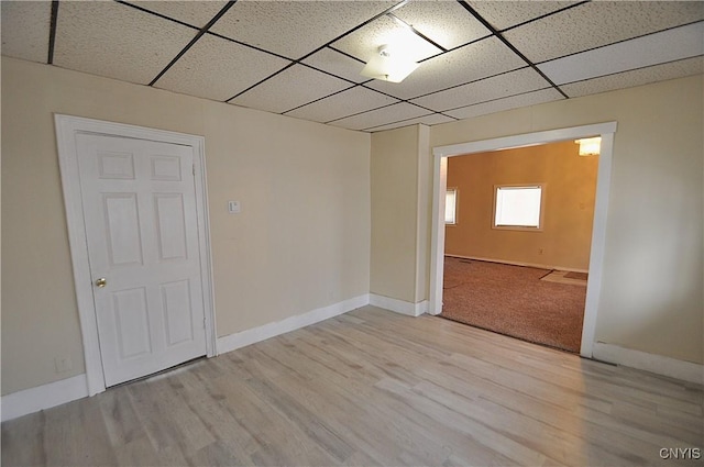 empty room featuring a drop ceiling and light hardwood / wood-style floors