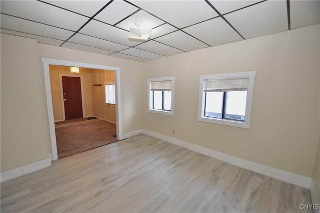 spare room with light hardwood / wood-style flooring and a paneled ceiling