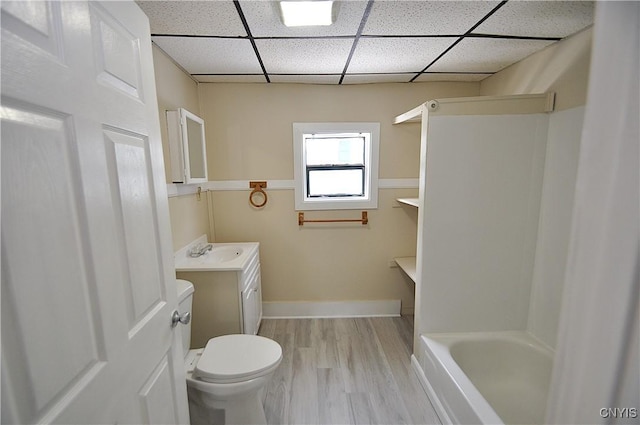 bathroom featuring wood-type flooring, vanity, toilet, a washtub, and a drop ceiling