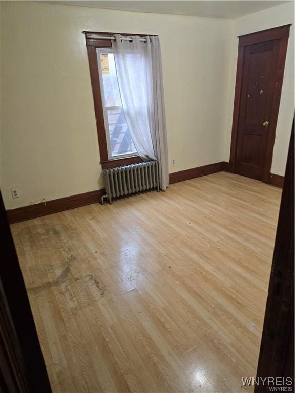 empty room with radiator heating unit and light hardwood / wood-style flooring