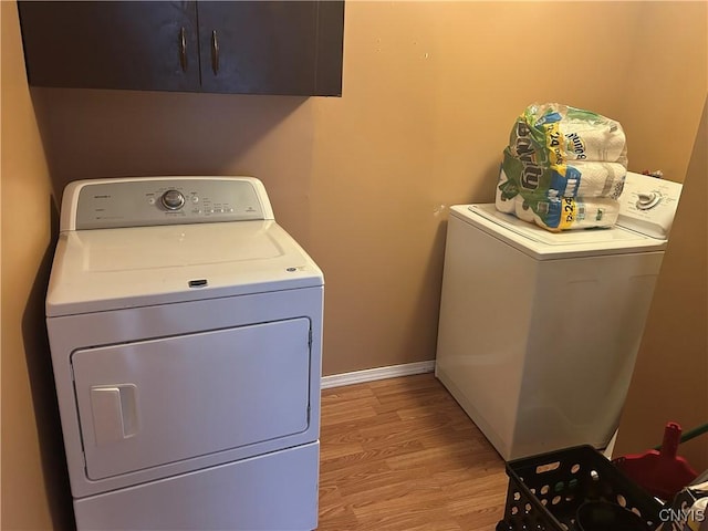 laundry room with washer and dryer, cabinets, and light wood-type flooring