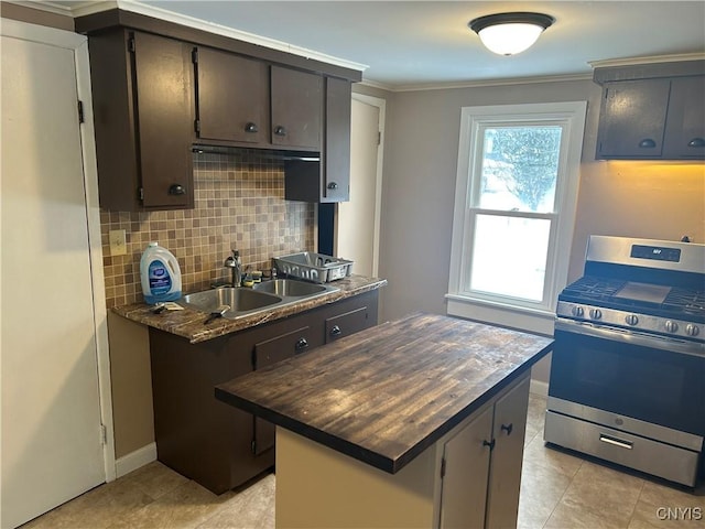 kitchen with dark brown cabinetry, a kitchen island, stainless steel gas stove, sink, and backsplash