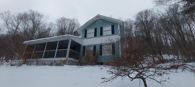 view of snowy exterior with a sunroom