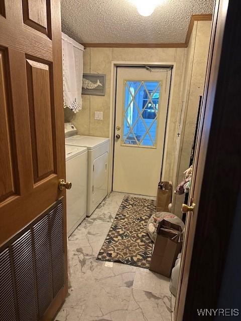 laundry room featuring a textured ceiling, ornamental molding, and washing machine and clothes dryer