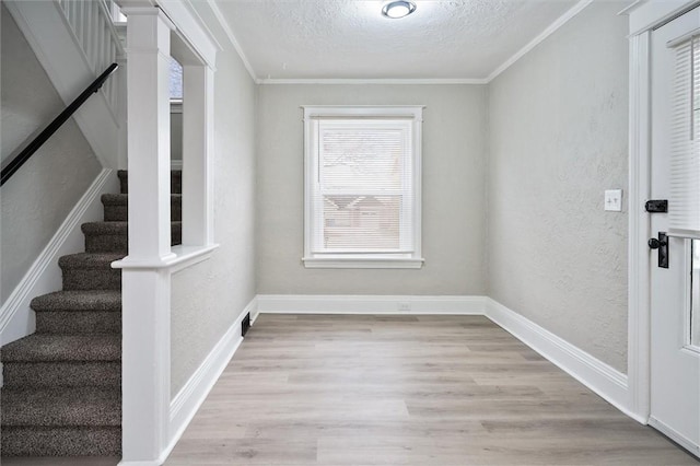 foyer with light hardwood / wood-style floors, a textured ceiling, and crown molding