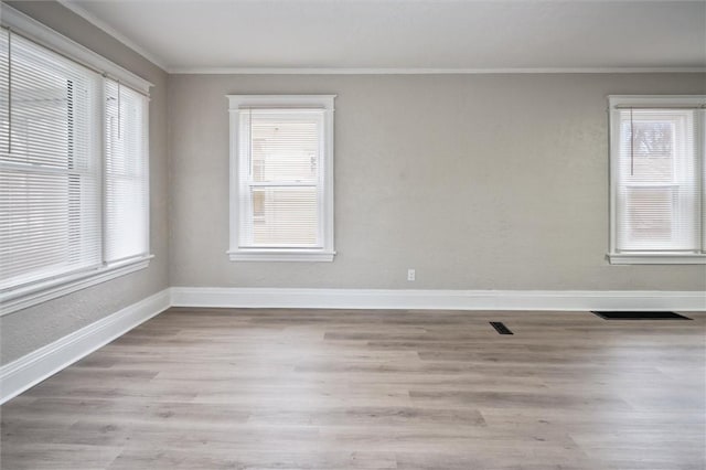 unfurnished room with ornamental molding, a healthy amount of sunlight, and light hardwood / wood-style floors