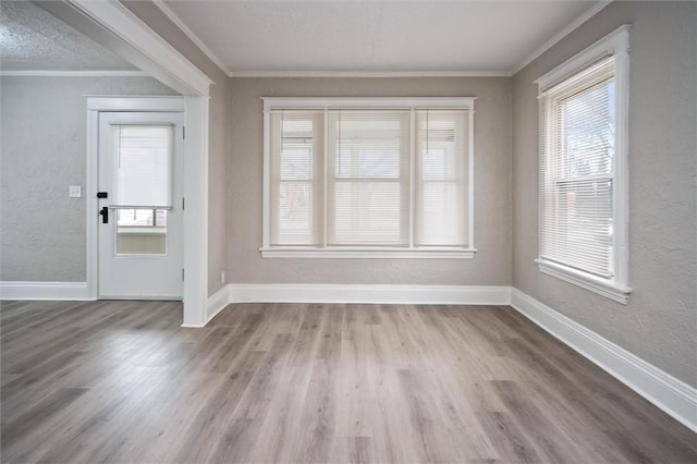 foyer entrance featuring a textured ceiling, ornamental molding, and light hardwood / wood-style floors