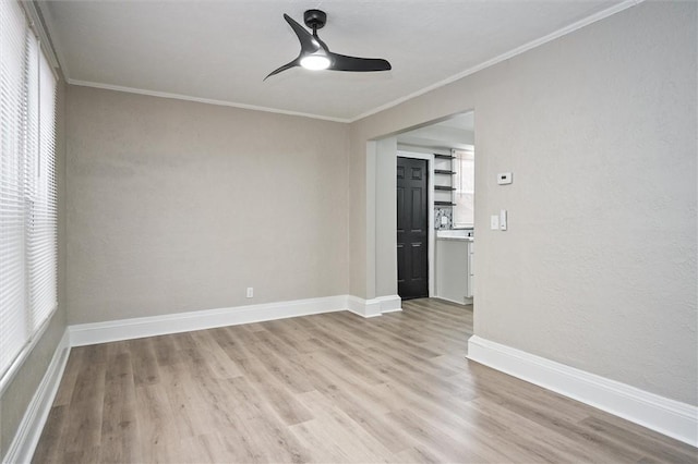 empty room featuring a healthy amount of sunlight, crown molding, and light hardwood / wood-style flooring