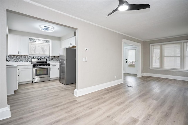 kitchen with light hardwood / wood-style floors, appliances with stainless steel finishes, tasteful backsplash, crown molding, and white cabinets