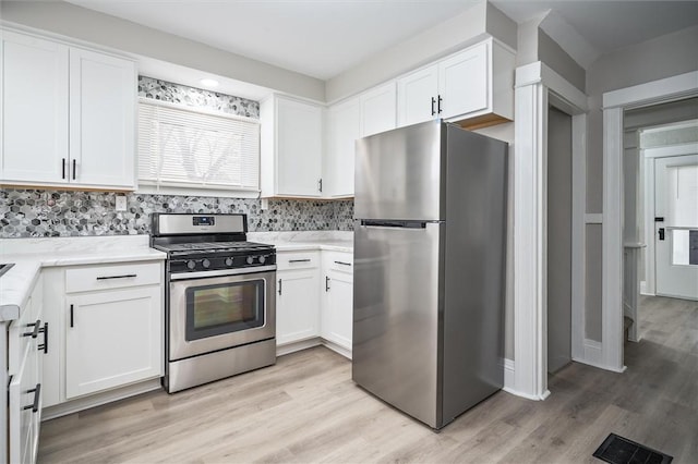 kitchen with light hardwood / wood-style flooring, backsplash, stainless steel appliances, and white cabinetry