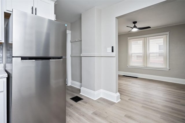 kitchen with white cabinetry, light hardwood / wood-style floors, stainless steel refrigerator, ceiling fan, and crown molding