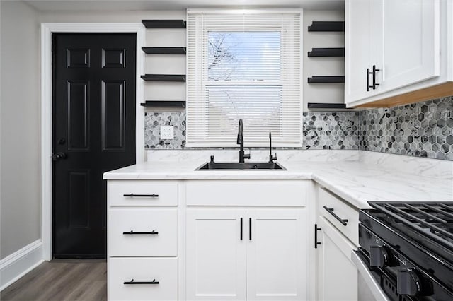 kitchen featuring light stone countertops, sink, white cabinets, and range with gas stovetop