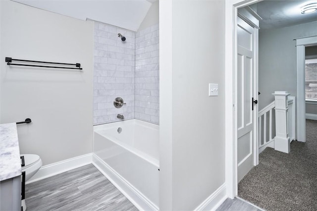 full bathroom featuring toilet, tiled shower / bath combo, vanity, and lofted ceiling