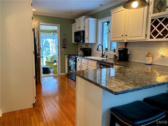 kitchen with backsplash, black appliances, kitchen peninsula, and white cabinets