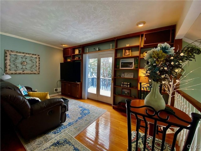 living room featuring ornamental molding, a textured ceiling, and light wood-type flooring