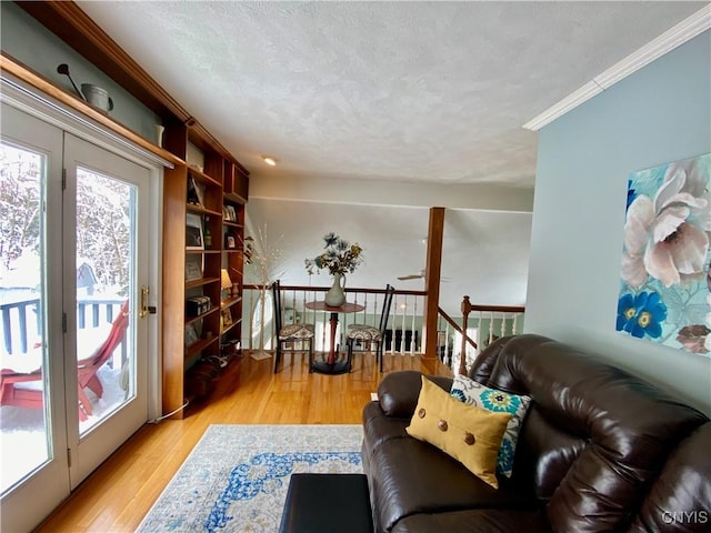 living room featuring light hardwood / wood-style flooring, ornamental molding, and a textured ceiling