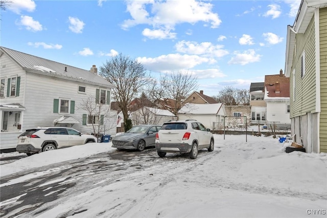 snow covered parking area with fence and a residential view