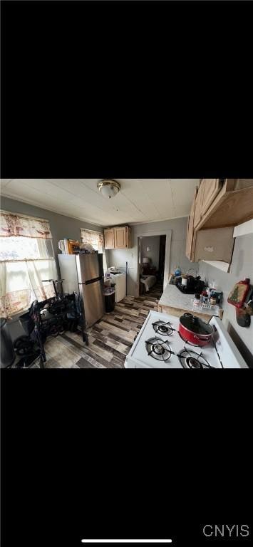 kitchen featuring washer / dryer, white gas stove, and freestanding refrigerator