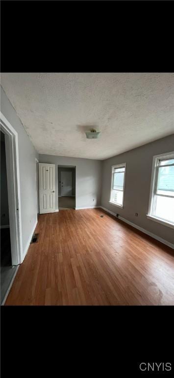 interior space with a textured ceiling, baseboards, and wood finished floors