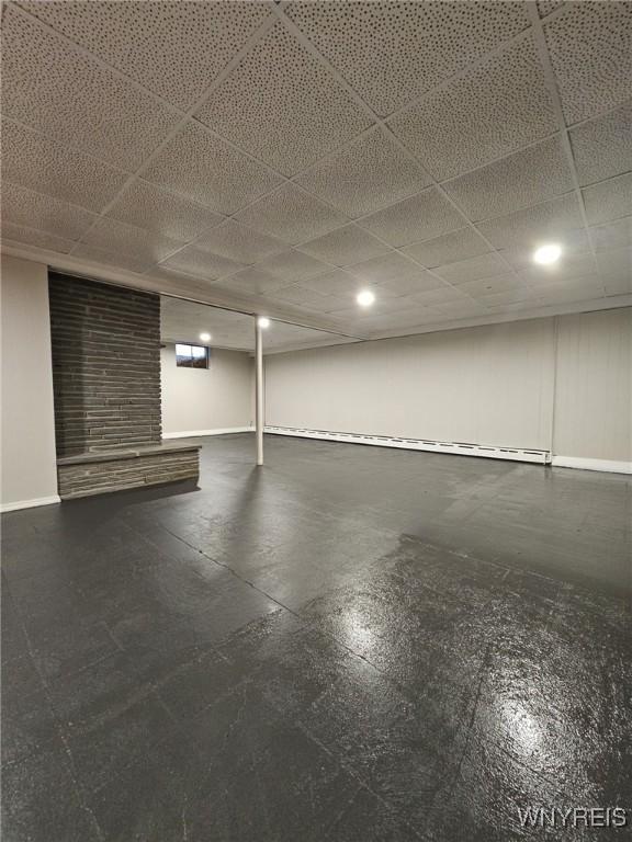 basement with a paneled ceiling and a brick fireplace