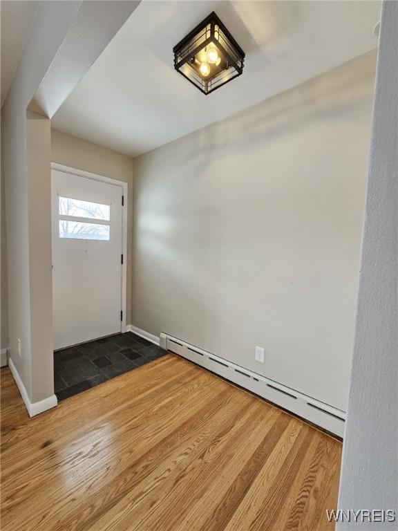 foyer entrance with a baseboard heating unit and wood-type flooring