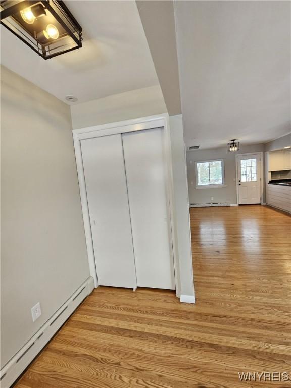 interior space with a baseboard heating unit and light hardwood / wood-style floors