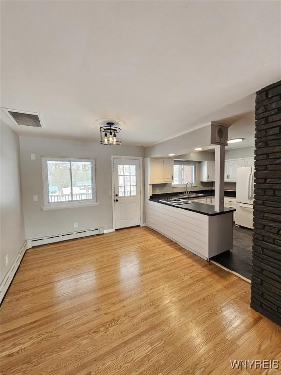 interior space featuring sink, a baseboard heating unit, and light hardwood / wood-style flooring