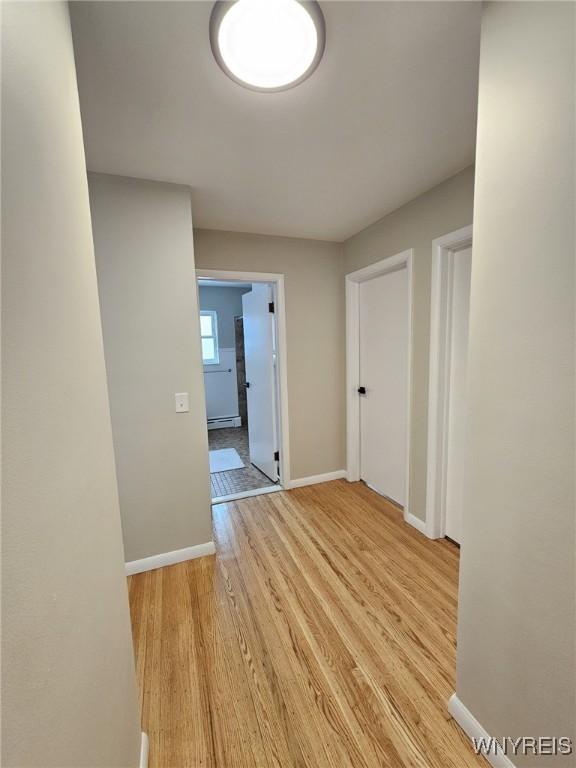 hall featuring light wood-type flooring and baseboard heating