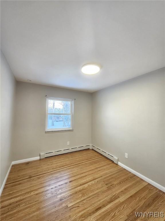 empty room with a baseboard radiator and light hardwood / wood-style flooring