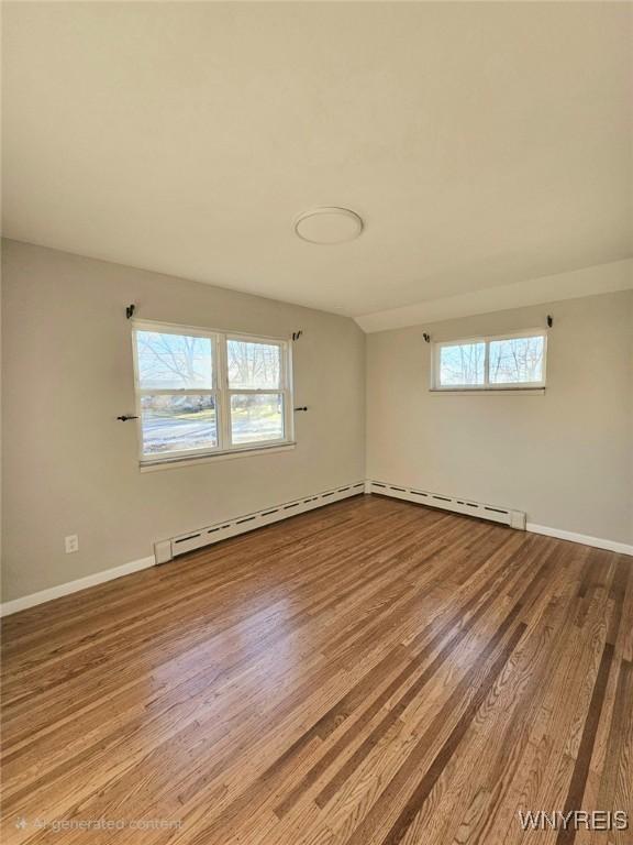 spare room with a baseboard radiator and hardwood / wood-style floors