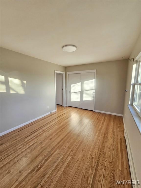 empty room with a baseboard radiator and light hardwood / wood-style flooring