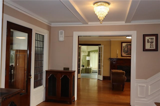 hallway with an inviting chandelier, crown molding, beam ceiling, and hardwood / wood-style flooring