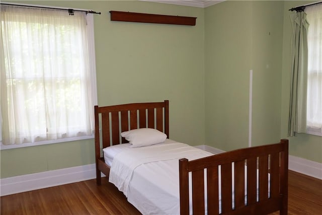 bedroom with dark hardwood / wood-style flooring, ornamental molding, and multiple windows